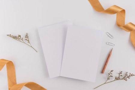 A wedding concept. Wedding Invitation, envelopes, cards Papers on white background with ribbon and decoration. Top view, flat lay, copy spaceの写真素材