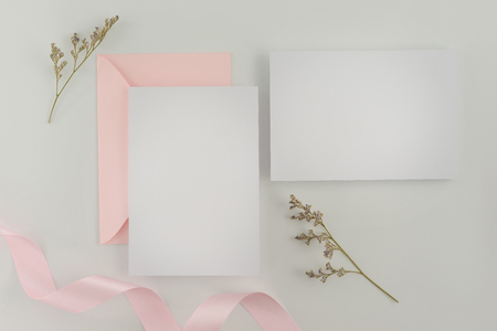A wedding mock up concept. Wedding Invitation, envelopes, cards Papers on white background with ribbon and decoration. Top view, flat lay, copy spaceの写真素材
