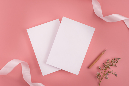 A wedding mock up concept. Wedding Invitation, envelopes, cards Papers on pink background with ribbon and decoration. Top view, flat lay, copy spaceの写真素材