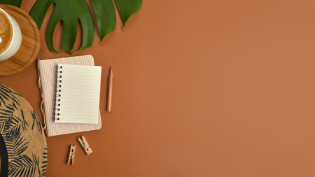 Flat lay, top view workspace with eye glasses, notebook, hat, pencil, green leaf, shoes and coffee cup on brown background. Summer stylish traveller blogger concept.の写真素材
