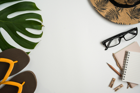 Flat lay, top view workspace with eye glasses, notebook, hat, pencil, green leaf, shoes and coffee cup on white background. Summer stylish traveller blogger concept.の写真素材