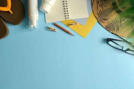 Flat lay, top view workspace with eye glasses, notebook, hat, sun block, shoes and coffee cup on blue background. Summer stylish traveller blogger concept.の写真素材