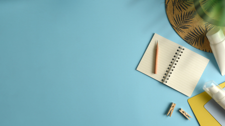 Flat lay, top view workspace with eye glasses, notebook, hat, sun block, shoes and coffee cup on blue background. Summer stylish traveller blogger concept.の写真素材