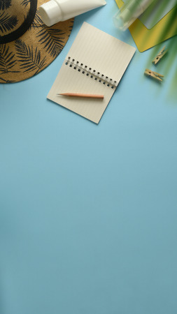 Flat lay, top view workspace with eye glasses, notebook, hat, sun block, shoes and coffee cup on blue background. Summer stylish traveller blogger concept.の写真素材