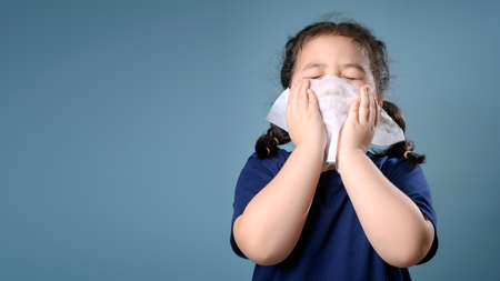 Little asian girl sick and sad with sneezing on nose and cold cough on tissue paper becauseweak or virus and bacteria from dust weather and kindergarten and kindergarten school for medical.の写真素材