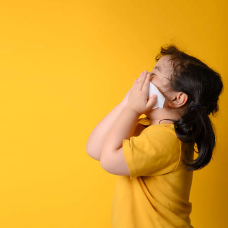Little asian girl sick and sad with sneezing on nose and cold cough on tissue paper becauseweak or virus and bacteria from dust weather and kindergarten and kindergarten school for medical.の写真素材