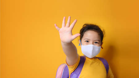 Little asian girl wearing mask for protect pm2.5 or Covid-19 and  show stop hands gesture for stop corona virus at school. E-learning or Home schooling education concept. New normal.Covid-19 coronavirus.の写真素材
