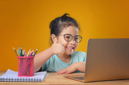 A Happy little asian girl studying online learning class with online video call zoom teacher at home. E-learning or Home schooling education concept. New normal.Covid-19 coronavirus.Social distancing.の写真素材