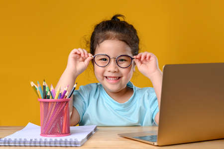 A Happy little asian girl studying online learning class with online video call zoom teacher at home. E-learning or Home schooling education concept. New normal.Covid-19 coronavirus.Social distancing.の写真素材