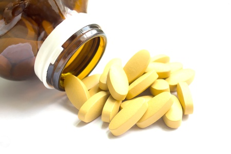 Yellow pills pouring out of the brown bottleの写真素材