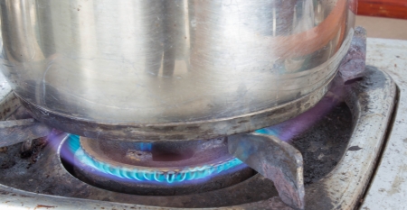Fire under the cooking pot on the Old gas stoveの写真素材
