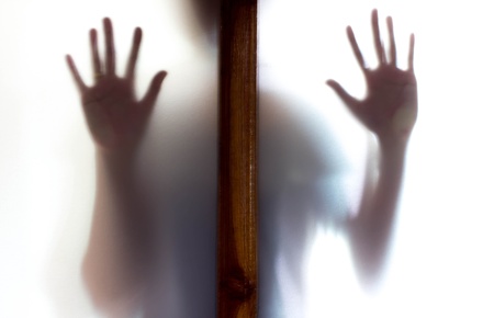 Shadow of woman standing behind door frosted glassの写真素材