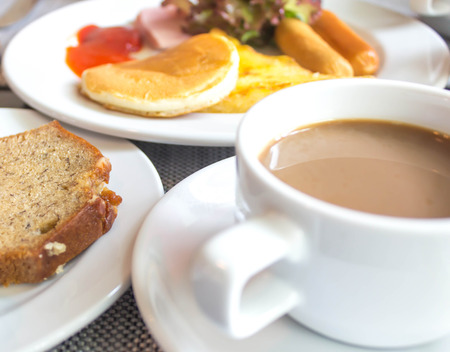 Coffee cup and saucer on the table with breakfast.の写真素材