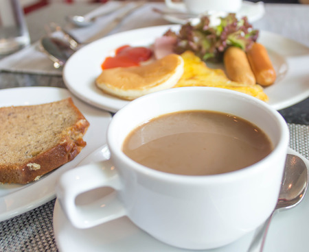 Coffee cup and saucer on the table with breakfast.の写真素材