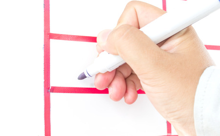 hand is ready for drawing with blue marker. Isolated on white boardの写真素材
