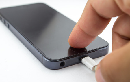 Charging of mobile phone on white background.