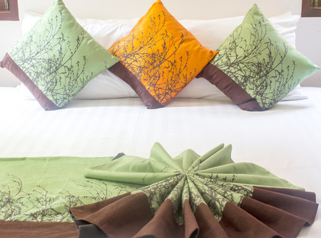 Three colorful striped pillows on white bed.の写真素材