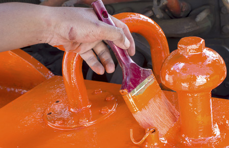 A hand is working with paint brush with orange paintの写真素材