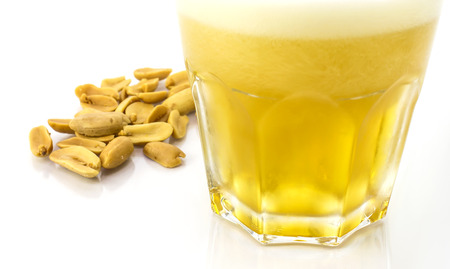 Beer in glass and fried  peanuts on white backgroundの写真素材