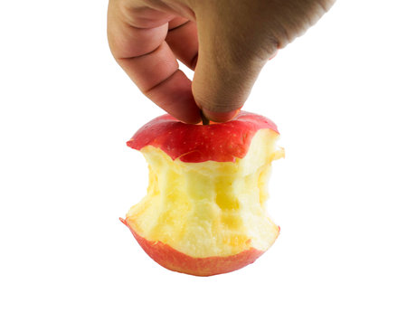 Bite red apple core in hand on a white backgroundの写真素材