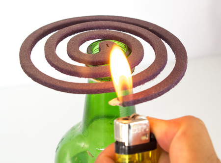 Mosquito Repellent  and lighter in hand on white backgroundの写真素材