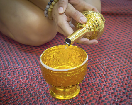 Buddhist's grail pouring water  sit on matの写真素材