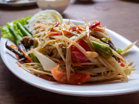 Som Tam (Spicy Papaya Salad) in a plate on a table.の写真素材