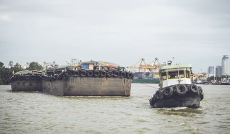 Tug boat towing a cargo boat in the riverの写真素材