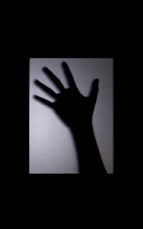 Shadow blur of two hand behind the mirror door.  Halloween concept is background in black and white tone picture style in light turned down lowの写真素材