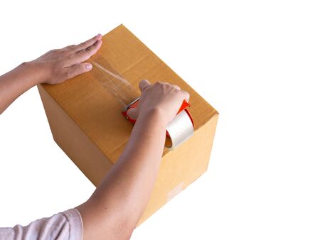 Hand holding roll of clear plastic packing tape and brown box isolated on white background.の写真素材