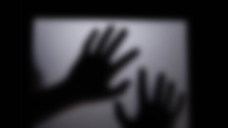 Defocused blur shadow hand behind the mirror door. Halloween concept is background in black and white tone picture style in light turned down low,の写真素材