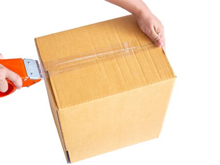 Hand holding roll of clear plastic packing tape and brown box isolated on white background.の写真素材