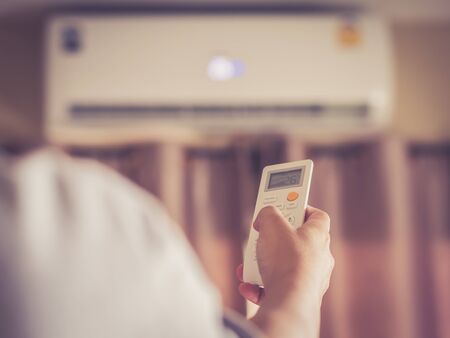 Hand holding with remote control directed on the conditioner,retro styleの写真素材