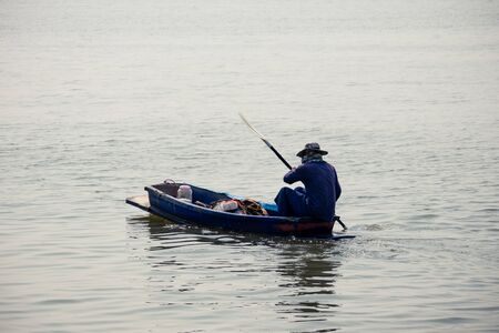 the man rowing a old small wooden rowboat dinghy in the riverの写真素材
