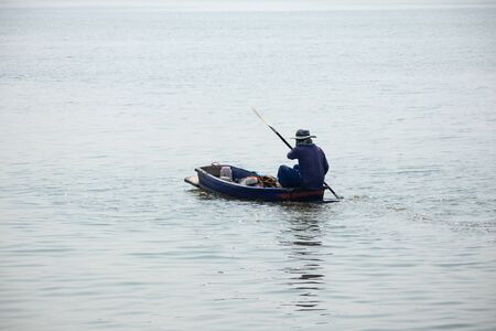 the man rowing a old small wooden rowboat dinghy in the riverの写真素材