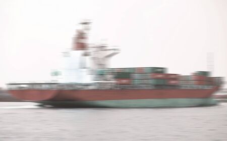 commercial container ship on river ,Logistic and navigation concept. A freight boat at the blur shore backgroundの写真素材