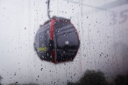 Cable car above green forest in misty clouds and water drops falling down on windowの写真素材