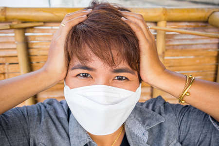 Asian female stay at home with protective face mask,She is irritated and anxious.の写真素材