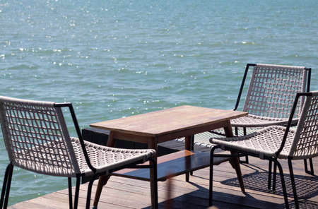 wooden table with chairs and deck chairs.background of sea.の写真素材