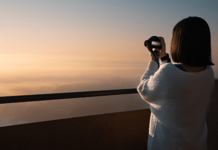photographer traveler take photo on video camera closeup on background autumn foggy mountain, tourist shooting nature mist landscape outdoor, hobby concept copy spaceの写真素材