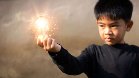 Boy holding light bulbs, ideas of new ideas with innovative technology. concept creativity with bulbs that shine glitter and inspiration, innovative technology in science and communication conceptの写真素材
