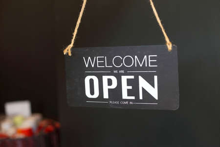 Welcome we're open vintage black and white retro sign on a coffee glass door cafe or restaurant....