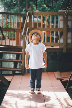 Handsome four-year-old Thai boy Put on a white t-shirt, a hat, stand up and look up.の写真素材