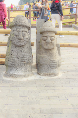 Twin Jeju idols (Dolharubang, the "grandfather stones" ) in Seongsan Ilchulbong ("Sunrise Peak"), one of the UNESCO nature tourism site on Jeju Island in South Koreaの写真素材