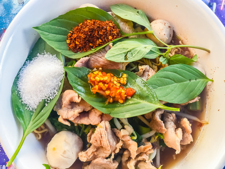 Popular street food in Thailand, Spicy pork noodle that consisted of pork ball, pork meat, basil or thyme, bean sprouts, morning glory, noodle and creamy soup which favouring with sugar, fish sauce, chilli and vinegar marinadeの写真素材