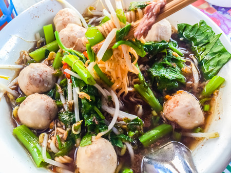 Popular street food in Thailand (Kuai Tiao Moo Namtok) that consisted of pork ball, pork meat, basil or thyme, bean sprouts, morning glory, noodle and creamy soup which favouring with sugar, fish sauce, chilli and vinegar marinadeの写真素材