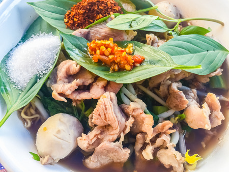 Popular street food in Thailand, Spicy pork noodle that consisted of pork ball, pork meat, basil or thyme, bean sprouts, morning glory, noodle and creamy soup which favouring with sugar, fish sauce, chilli and vinegar marinadeの写真素材