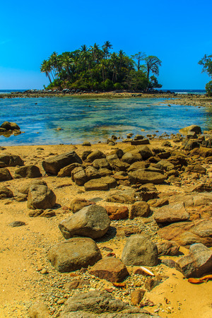 Lonely remote island with rock beach and tree when the sea water receded in blue sky and cloudy day backgroundの写真素材