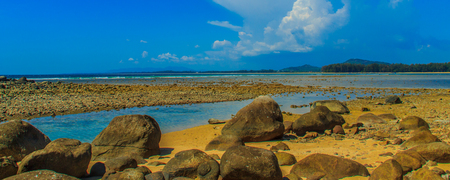 Beautiful rock stones on the beach when the sea water receded with dramatic blue sky background on the cloudy day.の写真素材