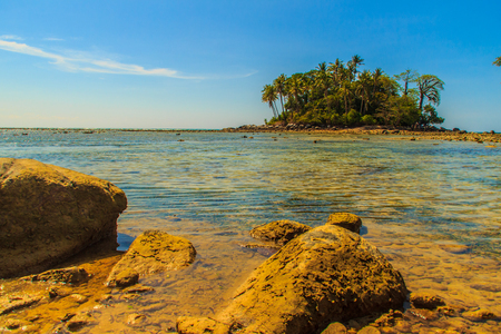 Lonely remote island with rock beach and tree when the sea water receded in blue sky and cloudy day backgroundの写真素材